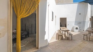 Una stanza con un letto, una lavatrice e un piccolo spazio all'aperto con tavoli e panche.