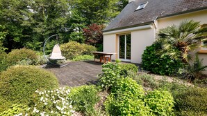A house with a wooden deck, a table, and various plants.