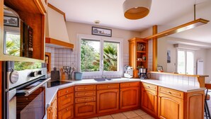 A kitchen with wooden cabinets, a built-in oven, a sink, and a window with a view of greenery.