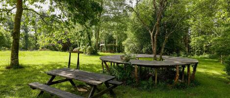 A picnic area with wooden tables and benches surrounded by lush greenery.