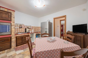 Eine kleine Küche mit Essbereich, einem Kühlschrank, einem Herd und einem Fernseher.