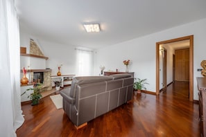 Ein Wohnzimmer mit Sofa, Kamin, Essbereich und Flur.