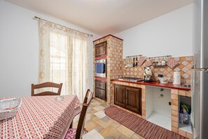 Eine kleine Küche mit Esstisch, Stühlen, Herd und Kühlschrank.