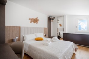 Una habitación de hotel con cama, una silla, una mesita de noche y ventana con vistas.