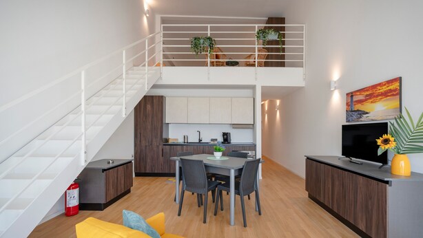 Un appartamento moderno con zona pranzo, cucina e un balcone con piante.