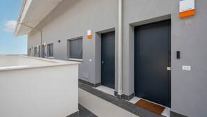 Un edificio moderno con diverse porte scure, facciata bianca e tetto piano.
