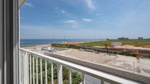 Vista da un balcone su un'area di parcheggio, una spiaggia e un cantiere edile.