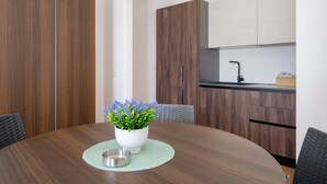Uma cozinha moderna com armários de madeira, uma mesa de jantar com uma planta em vaso e uma pia de aço inoxidável.