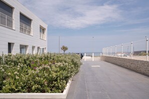 Un edificio moderno con un camino empedrado, un muro de piedra y una valla de metal.