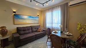 Un salon comprenant un canapé, une table à manger, des chaises, un tableau et un appareil de climatisation.