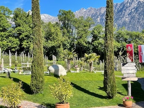 Un jardin agrémenté d’un panneau d’accueil, de chaises longues et offrant une vue sur les montagnes.