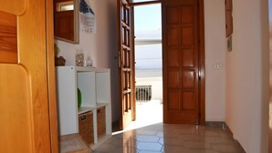 Un couloir avec une porte en bois, un réfrigérateur blanc et un sol carrelé.