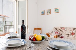 Een eettafel gedekt met borden, glazen, een fles wijn en een schaal fruit.