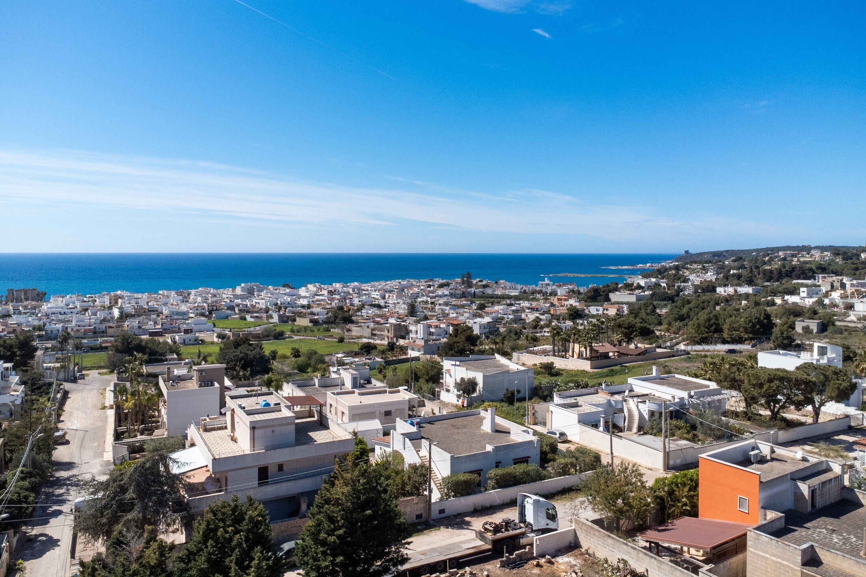 Un pueblo costero con edificios blancos, cielo azul despejado y el mar al fondo.