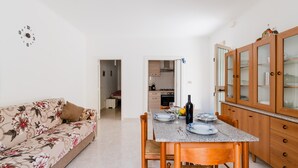 Un comedor con una mesa lista para dos personas, un sofá y armarios de madera.