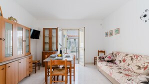 Una cocina moderna con armarios de madera, una mesa de comedor con sillas, un sofá y un televisor montado en la pared.