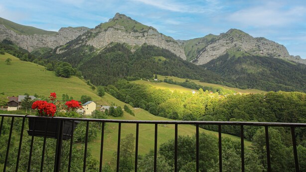 A mountainous landscape with a house and greenery.