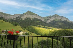 A mountainous landscape with a house and greenery.