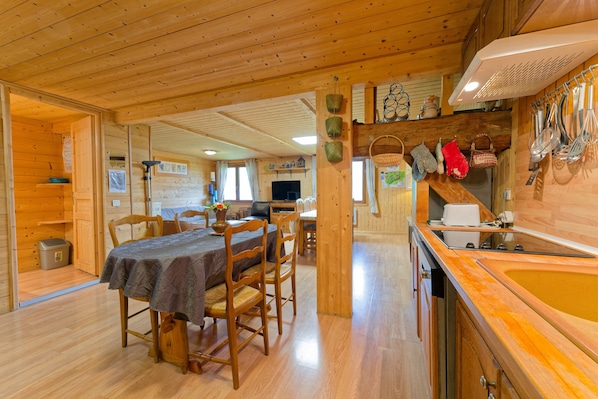 Un intérieur en bois comprenant un coin repas, une cuisine et une cheminée.
