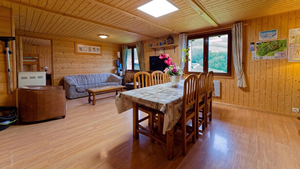 Un interior de madera con una mesa de comedor, sillas, un sofá y un televisor.