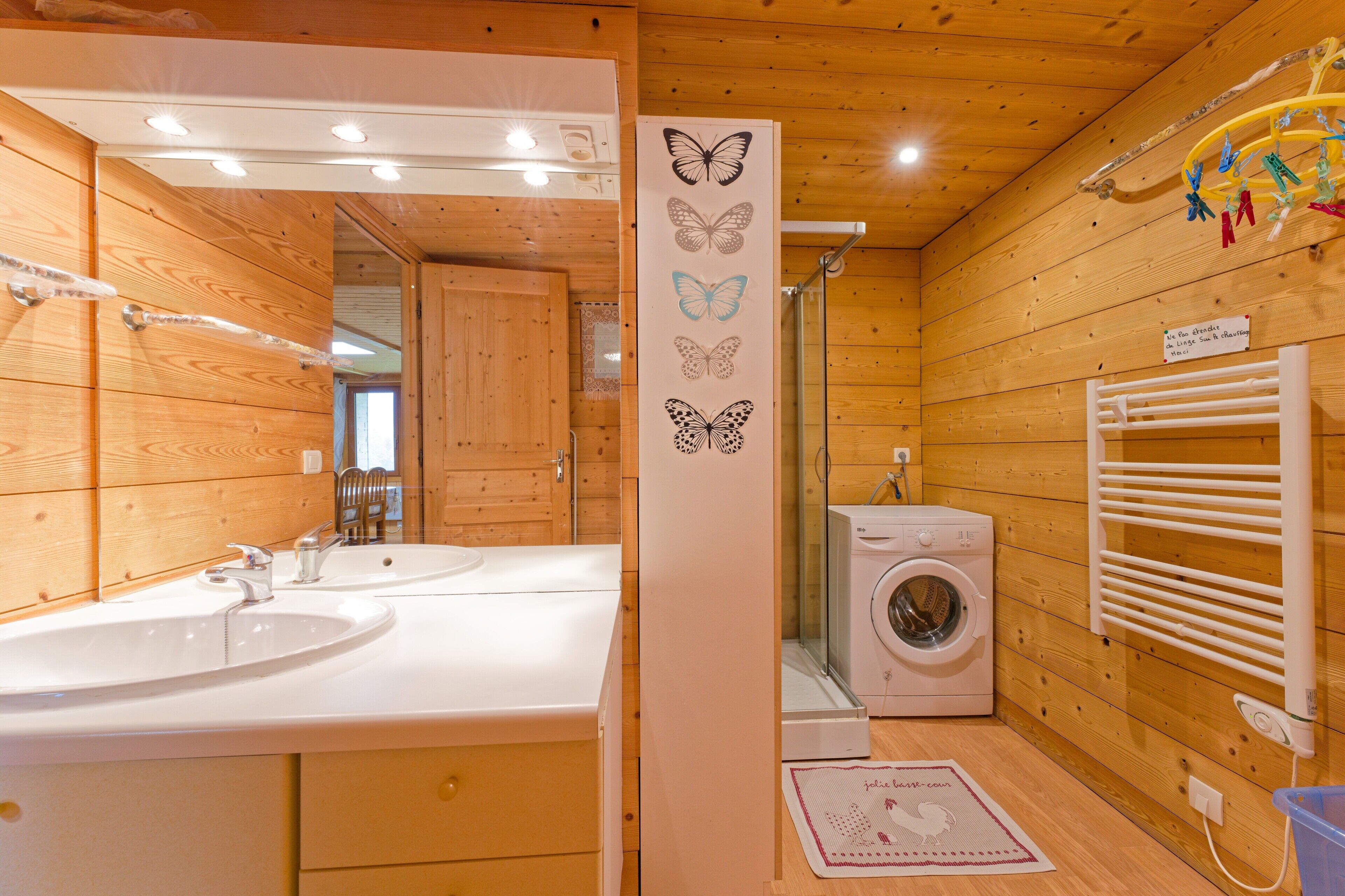 A wooden cabin bathroom with two sinks, a washing machine, and a towel rack.