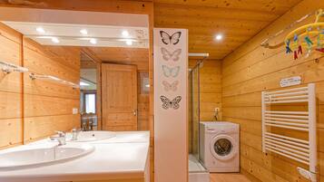 A wooden cabin bathroom with two sinks, a washing machine, and a towel rack.