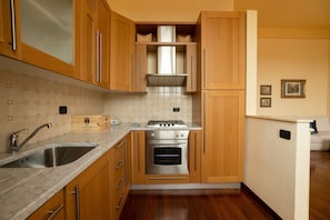 A kitchen with wooden cabinets, a stainless steel sink, a stove, and a built-in oven.