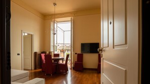 Un salón amplio con mesa y sillas de comedor, televisión y puerta corrediza de vidrio que da a un patio exterior.