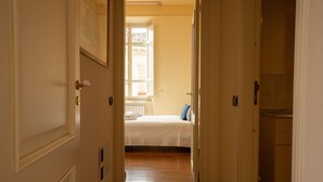 Un pasillo que conduce a un dormitorio con cama, ventana y puerta.