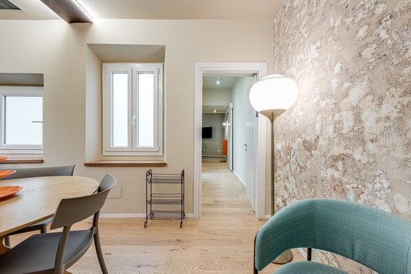 A modern kitchen with a dining table, chairs, a metal rack, and a light fixture.