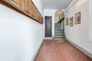A hallway with a wooden cabinet, a dark door, a staircase, and framed pictures on the wall.