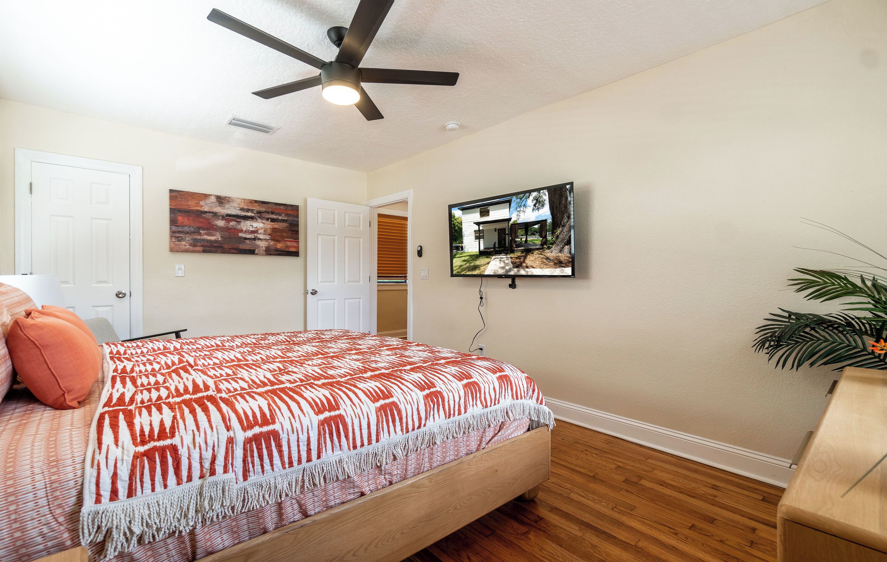 Una camera da letto con un letto, un ventilatore a soffitto, una TV e una pianta.