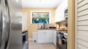 A compact kitchen with white cabinets, a stainless steel refrigerator, a window with blinds, and a built-in oven. - Remodeled unit steps from San Marco cafes and shops and near Riverwalk (Jacksonville)