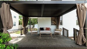 A covered patio area with wicker furniture and a bench, a white brick wall, and a metal railing. - Remodeled unit steps from San Marco cafes and shops and near Riverwalk (Jacksonville)