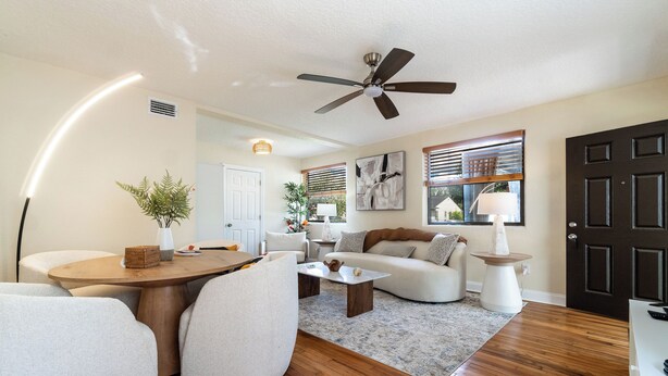 A living room with a wooden floor, a ceiling fan, a round coffee table, a sofa, and a dining table with chairs. - Remodeled unit steps from San Marco cafes and shops and near Riverwalk (Jacksonville)
