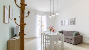 Uma sala de estar moderna com uma mesa de jantar branca, um sofá e obras de arte nas paredes.
