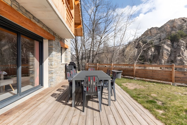 A deck with a table and chairs, a stone wall, and a wooden fence.
