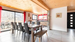 Een eetgedeelte met een houten plafond, een grote tafel met stoelen, een bank en uitzicht op het buiten.
