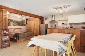 Una habitación acogedora con una cama, una mesa de comedor, armarios de madera y una zona de cocina.