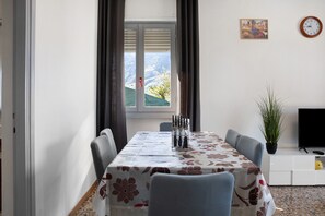 Un espace repas comprenant une table, des chaises, une horloge, un téléviseur et une plante.