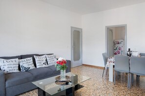 Un salon comprenant un canapé, une table basse en verre et un coin repas avec des chaises et une table.