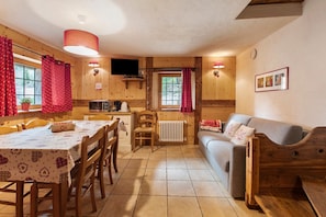 A cozy cabin interior with a dining table, chairs, a sofa, a TV, and a window with curtains. - Apartment 'Lo Trapey' with Shared Terrace, Shared Garden and Wi-Fi (Charvensod)