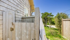 A wooden house with a sliding door leading to a covered porch.