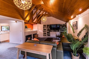 A modern living room with a wooden ceiling, a fireplace, a television, and a seating area.