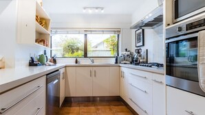 A modern kitchen with white cabinets, a stainless steel oven, and a window providing a view of the outdoors. - Epic Games Room | 3-min to Hot Pools | Pets OK (Hanmer Springs)