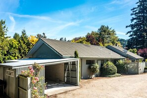 A single-story house with a covered porch, a fenced yard, and a gravel driveway.