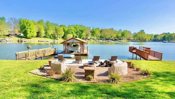 Um pátio à beira do lago com área de estar externa, um píer e um gazebo.