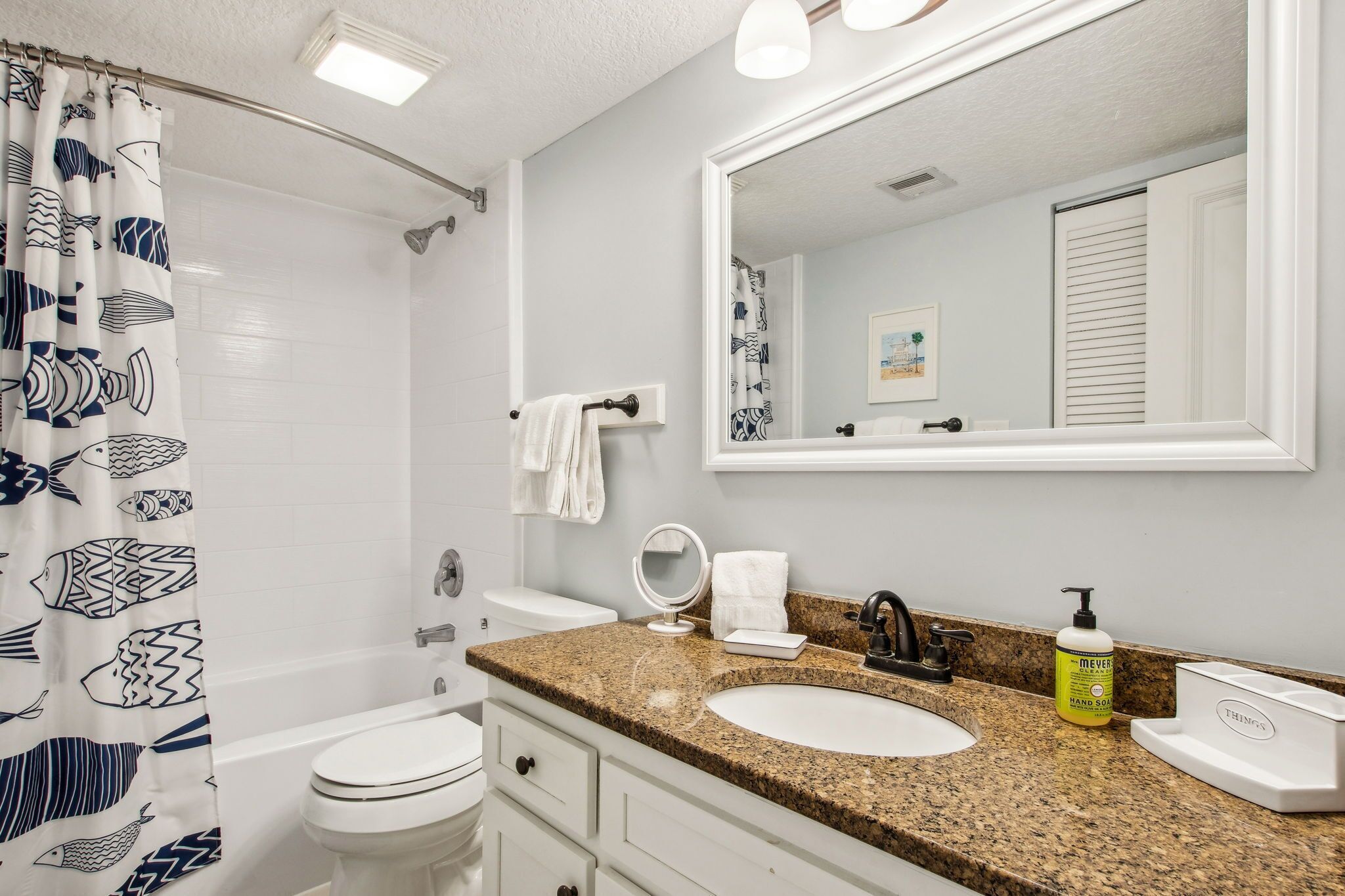 A bathroom with a shower, toilet, sink, and a large mirror.