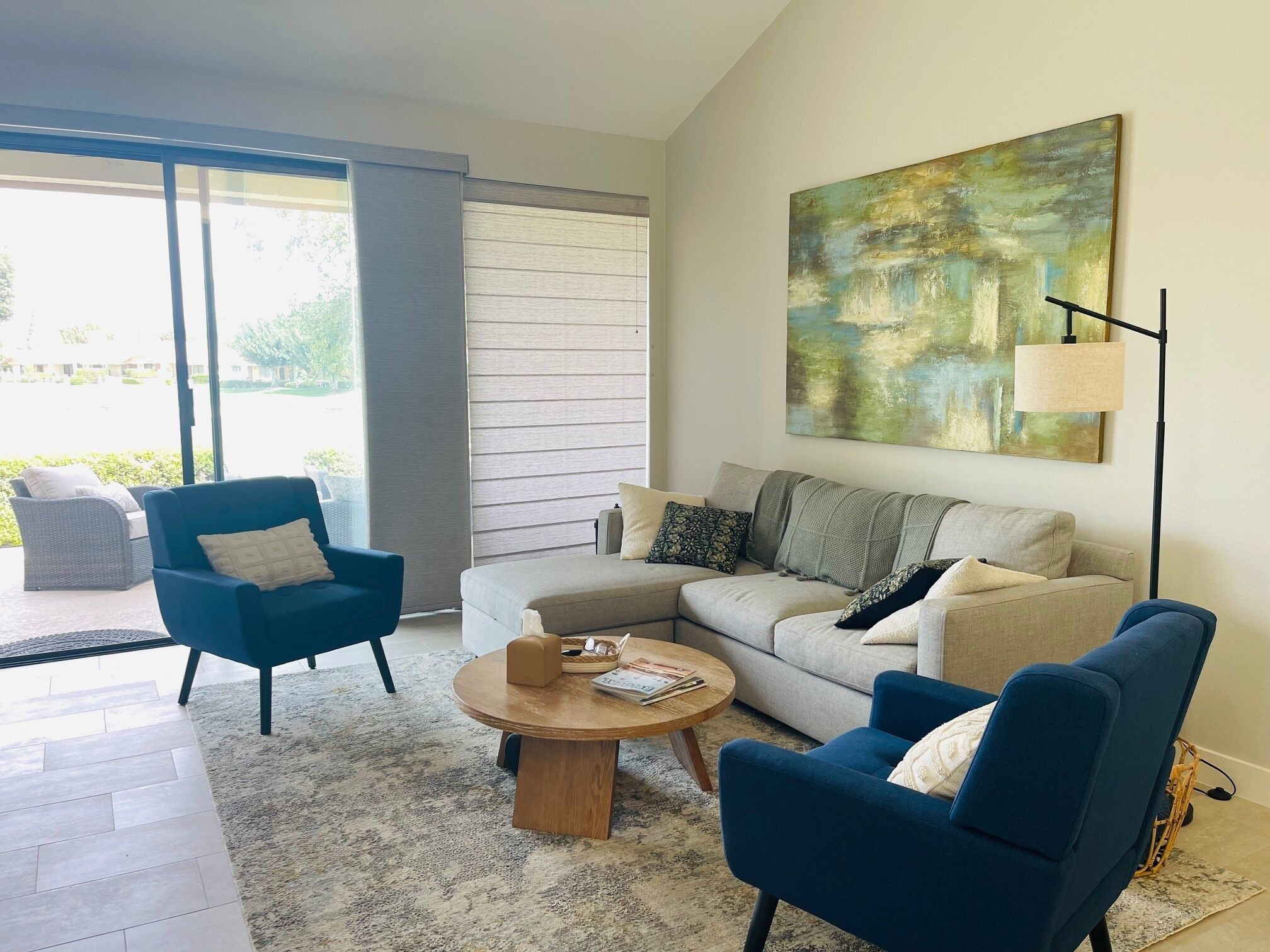Una sala de estar moderna con un sofá, sillones, una mesa de centro y un cuadro en la pared.