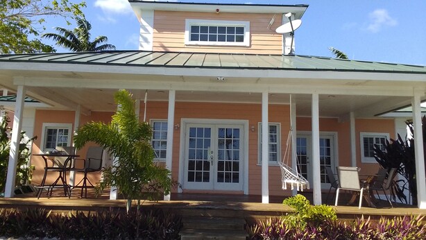 A two-story house with a covered porch, a small garden, and a satellite dish. - Tallis Palace. 1-bedroom apartment with WiFi, AC in sunny Freeport. Car offered. (Freeport)